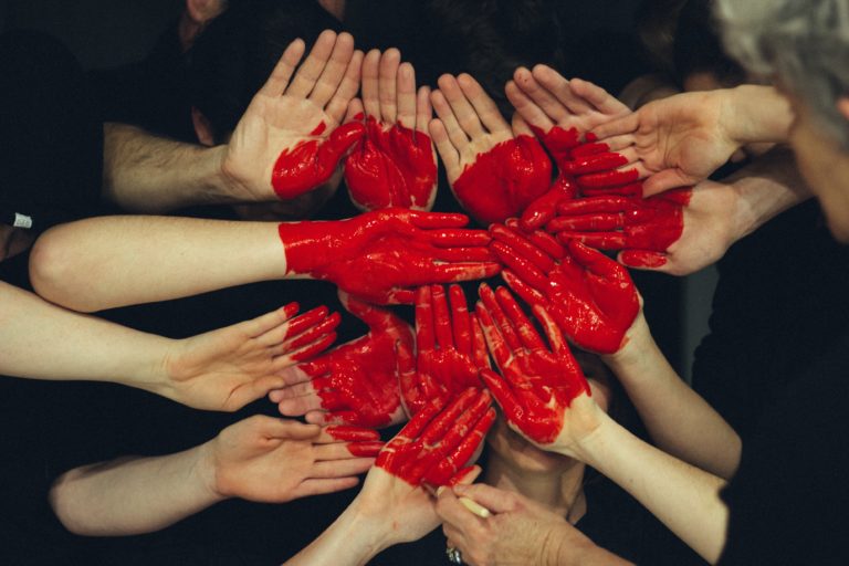 hands of many people and red heart drawn on them