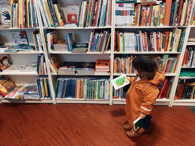 child in front of books on shelves