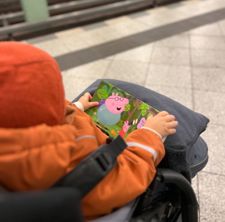 child in stroller with book